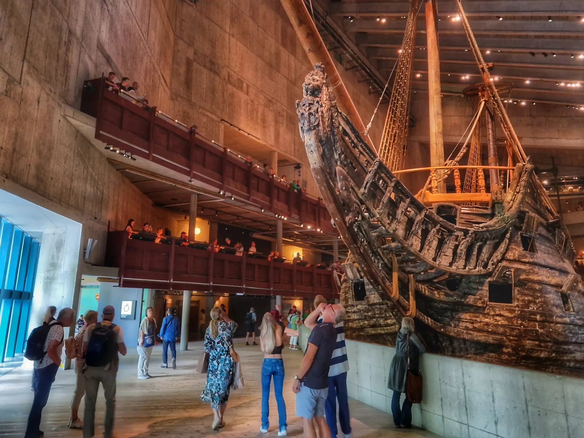 Interiör av Vasamuseet. Människor betraktar skeppet Vasa från marken och balkonger