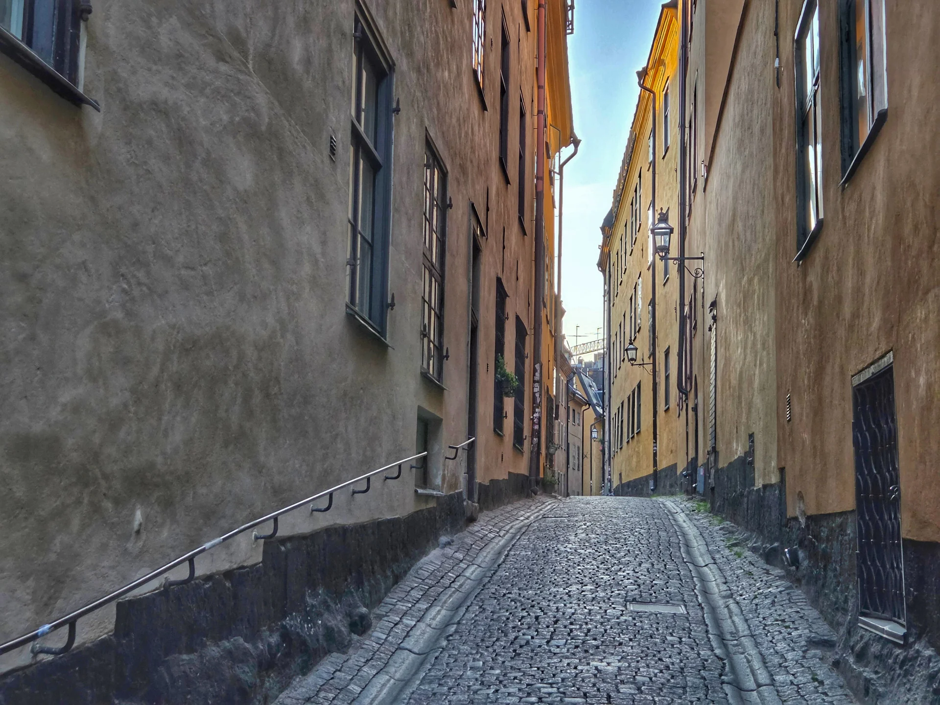 Smal, uppförslutande kullerstensgränd mellan gamla husväggar. Stadsvandring Gamla Stan
