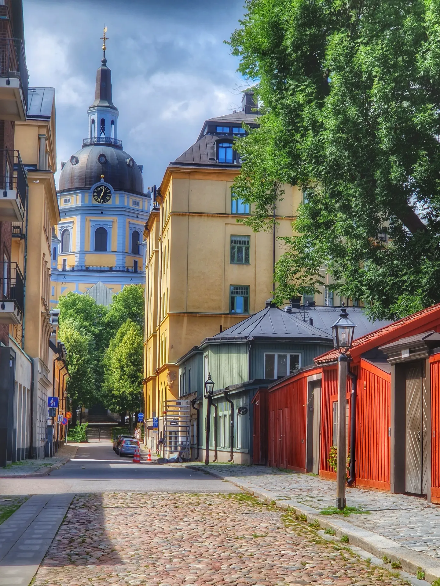 Gata med kullersten och färgglada hus. Kyrka med torn i fonden. Stadsvandring Södermalm