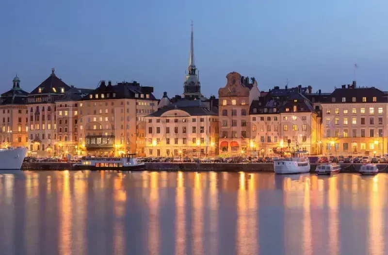Stockholms Gamla Stan vid vatten, kvällsbelysning i byggnader speglas i vattnet