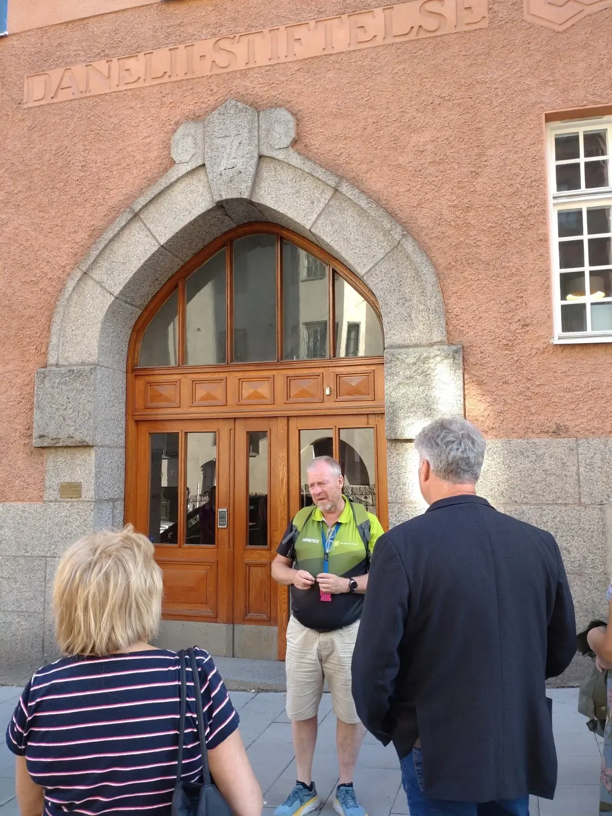 Person som håller en stadsvandring vid Daneliistiftelsen. Två personer lyssnar