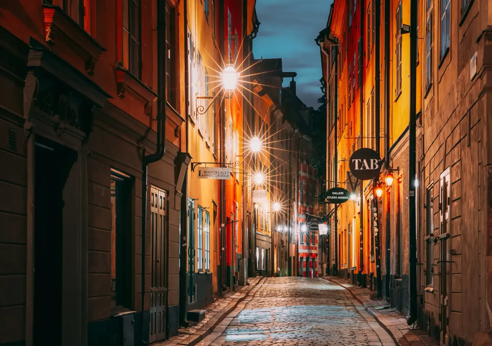 Gata i Gamla Stan, Stockholm, nattetid. Gult och orange ljus från gatlyktor och husfasader