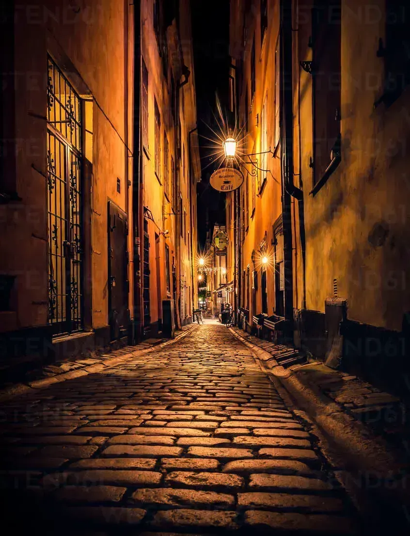 Gata i Gamla Stan, Stockholm, belyst av gatlyktor. Kullerstenar