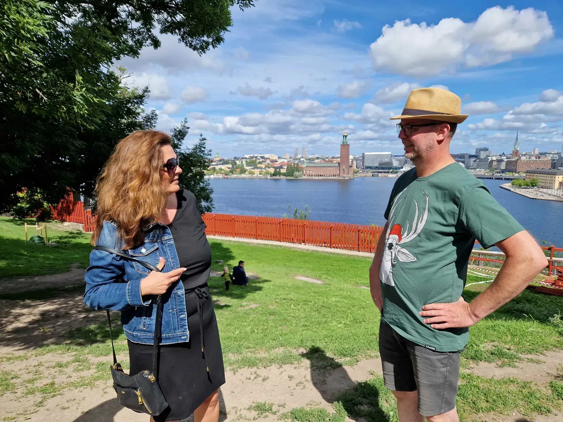 Två personer samt Stockholms stadshus i bakgrunden. Mariaberget Södermalm