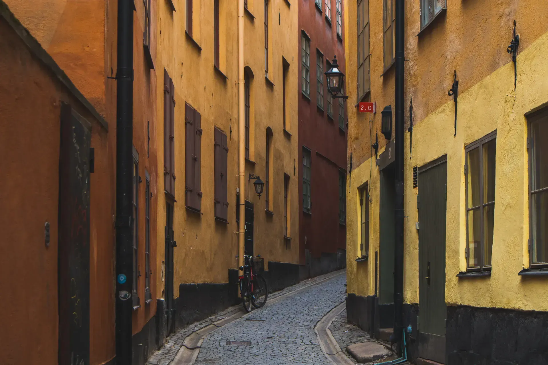 Gata i Gamla Stan med kullersten och hus i gult och orange. Cykel står parkerad