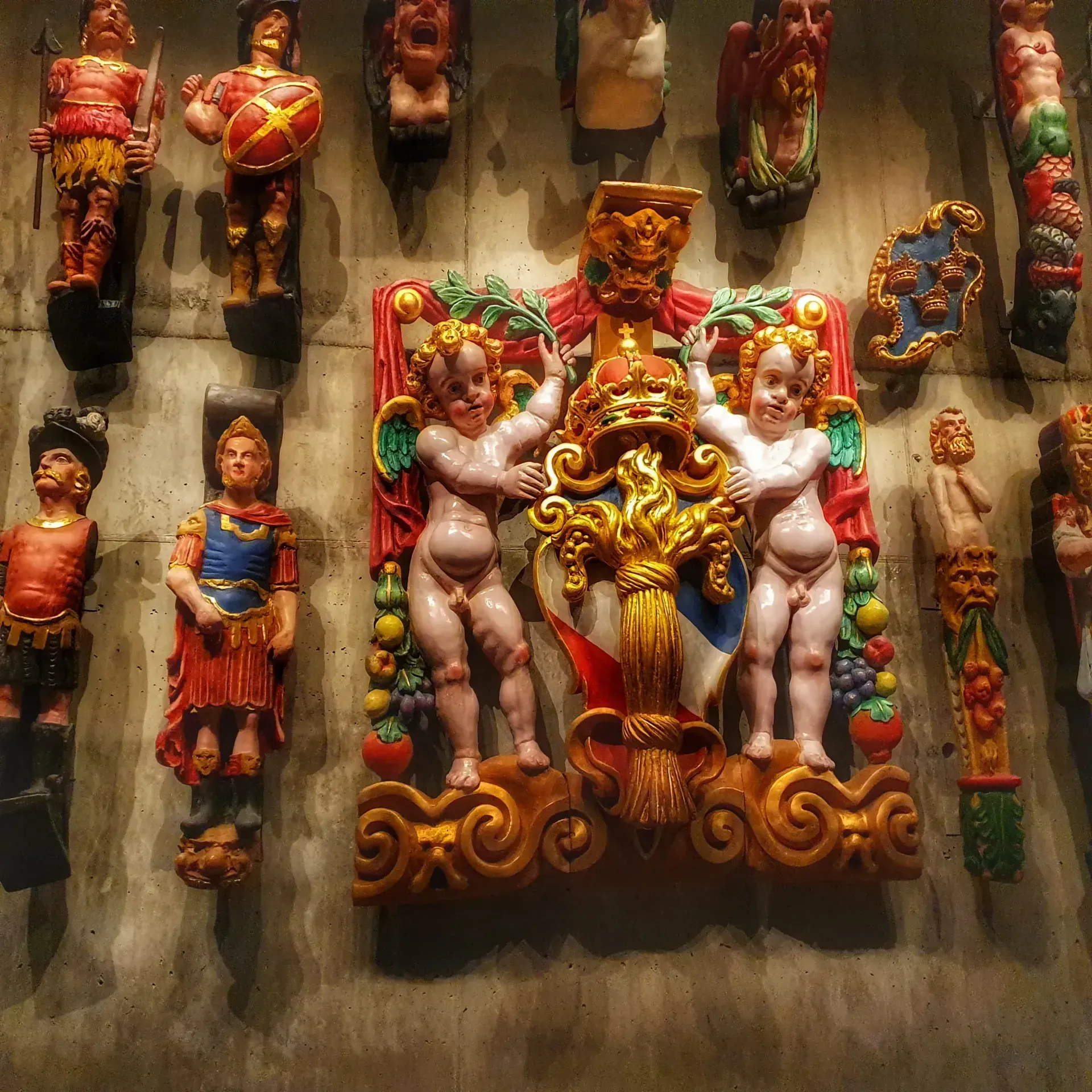 Detaljerade, färgstarka träskulpturer på en vägg. Några ser ut att vara från Vasamuseet