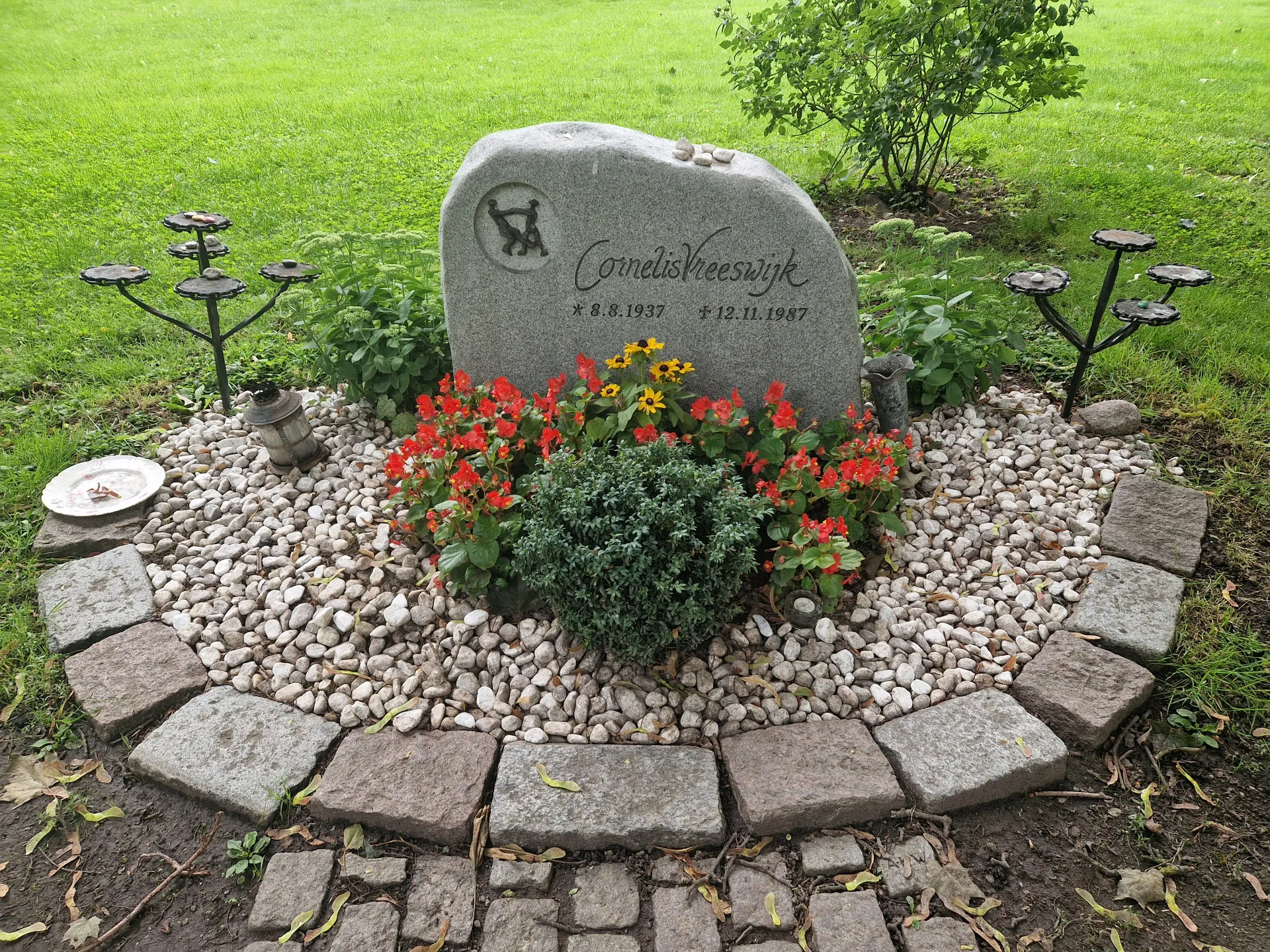 Gravsten med texten "Cornelis Vreeswijk", födelse- och dödsdatum. Blommor och vita stenar