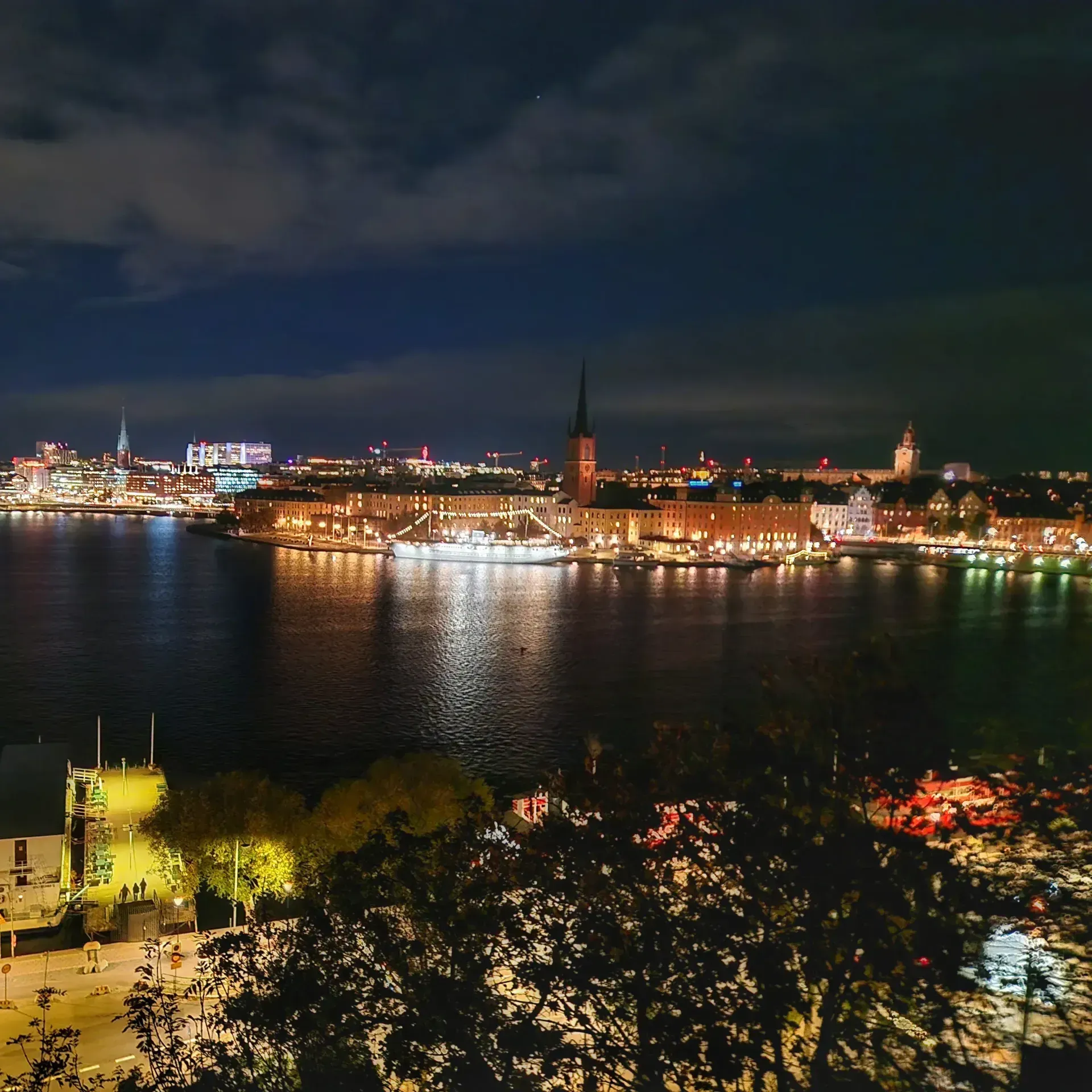Stockholm i nattbelysning sett från Söders höjder. Vatten, byggnader och molnig himmel
